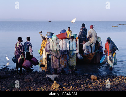 Kenia, Provinz Nyanza, Kisumu. Die ganze Nacht gefischt im seichten Wasser des Lake Victoria Kavirondo Golf in der Nähe von Kisumu, zurück Fischer Dunga Strand kurz nach Sonnenaufgang wo drängeln sich Männer und Frauen, um ihren Fang von Tilapia, Viktoriabarsch und die kleinen Engraulicypris Arten zu kaufen. Die meisten Bootsbesitzer haben zwei Mannschaften um ihr Handwerk zu einen 24-Stunden-Zyklus arbeiten zu ermöglichen. Stockfoto