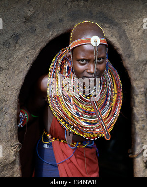 Kenia, Trans-Mara, Lolgorien. Ein junges Maasai Mädchen in all ihrer Pracht hält am Eingang zu ihrer Mutter nach Hause. Stockfoto