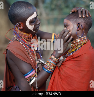 Kenia, Trans-Mara, Lolgorien. Junge Maasai Mädchen schmücken ihre Gesichter mit Ocker und Lehm in der Vorbereitung für einen Tanz. Stockfoto