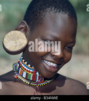 Kenia, Kajiado, Magadi. Ein Junge Maasai Mädchen trägt einen Holzstopfen im Ohr durchbohrt um das Ohrläppchen zu verlängern. Stockfoto