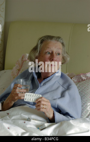 alte Dame im Bett mit Pillen, die betroffenen suchen Stockfoto
