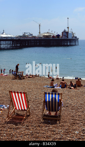 Menschen entspannen in Liegestühlen am Strand von Brighton an einem heißen Sommertag Stockfoto