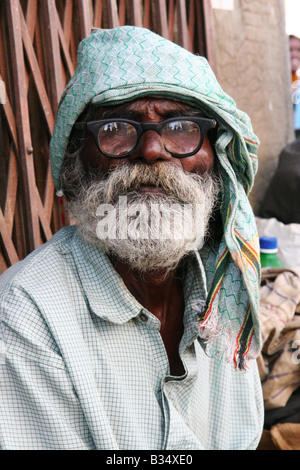 Ein Mann in Gläsern sitzt auf einer Stufe, die Schatten in Bangalore, Indien zu genießen. Er hat einen weißen Bart. Stockfoto