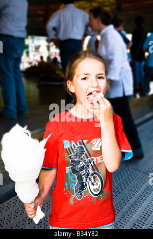 Junges Mädchen essen Zuckerwatte auf Kirmes Stockfoto