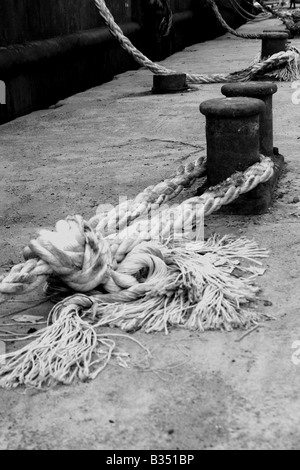 Schwarz / weiß Bild von ein Seil Boot zum Liegeplatz Beitrag am Ufer Stockfoto