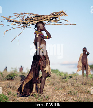 Kenia, Turkana, Nachola. In den semi-ariden Gegenden Turkanaland haben Frauen, große Entfernungen um Feuerholz zu sammeln. Wie andere nilotischen Menschen lädt Turkana Frauen Gleichgewicht schwer auf ihren Köpfen mit anmutigen Beförderung und Selbstsicherheit. Die Kleidung der Frau ist typisch für verheiratete Frauen des Stammes. Stockfoto