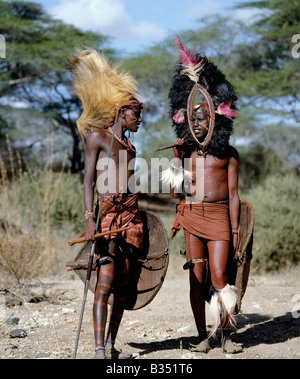 Kenia, Kajiado, Ilpartimaro. Zwei Massai-Krieger in voller Montur. Der Kopfschmuck des Mannes auf der linken Seite besteht aus der Mähne eines Löwen, während man auf der rechten Seite mit schwarzen Straußenfedern gesäumt ist. Ihre traditionellen Waffen gehören lange Klinge Speere und Schilde sind aus Büffelleder. Stockfoto