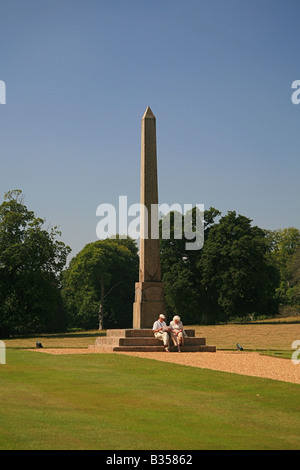 Ein Mann und eine Frau ruht am Fuße des steinernen Obelisken auf dem Gelände des Kingston Lacey House in der Nähe von Wimborne Minster, Dorset UK Stockfoto