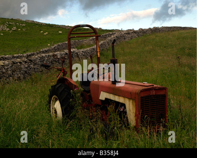 Verlassenen alten roten Traktor in einem Feld neben einer Trockensteinmauer in den Yorkshire Dales allein stehend Stockfoto