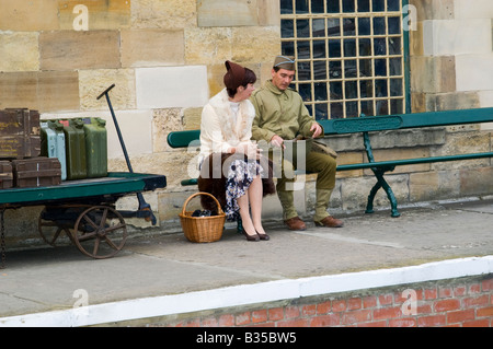 Kriegszeit Paare, junge Mann & Frau setzte sich auf eine Bank in Pickering. Lebendige Geschichte 1940er Jahre Weltkrieg Krieg Krieg Wochenende, North Yorkshire, England, Großbritannien Stockfoto