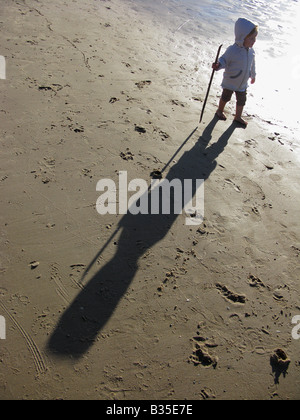 Kind Mädchen allein zu Fuß an der Küste mit Gehstock Stockfoto