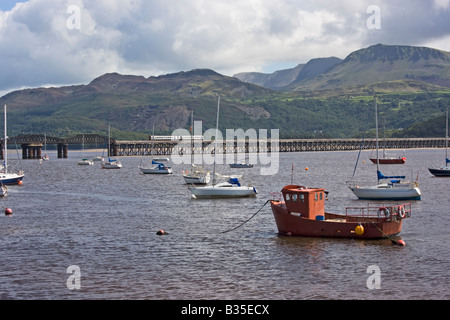 Boote mit Zug überqueren auf der Brücke in Barmouth Mitte Wales an der Mündung der Mywddach verankert. Stockfoto