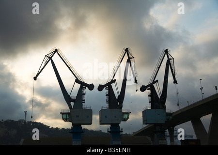 Spanien Barcelona drei Kräne zum Abladen von Container und Ladung von Schiffen gegen bewölktem Himmel Stockfoto