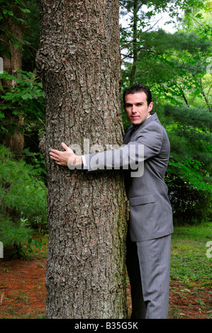 Ein Geschäftsmann im Anzug umarmt einen Baum darstellt, Treehugger und corporate Umweltschutz Stockfoto