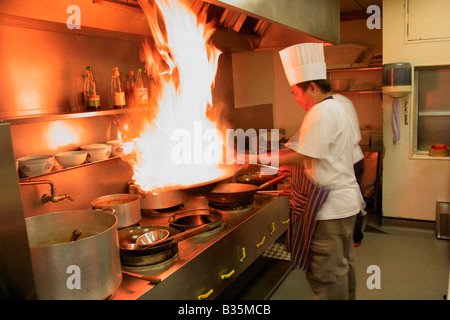 Männlichen Thai Koch mit flammender Wok in einer Restaurantküche, orientalische Küche Stockfoto