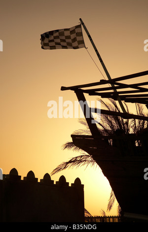 Karierte Flagge auf die Dhow Boot an der 2007 Formel 1 Grand Prix von Bahrain mit Sonnenuntergang Palm Tree und Arabische Burg fort Stockfoto