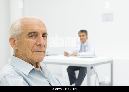 Arzt arbeiten am Schreibtisch, Fokus auf ältere Patienten im Vordergrund Stockfoto