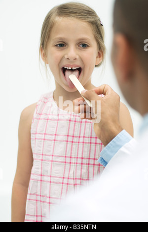 Arzt untersucht ein Mädchen die Kehle mit einer Zunge depressor Stockfoto