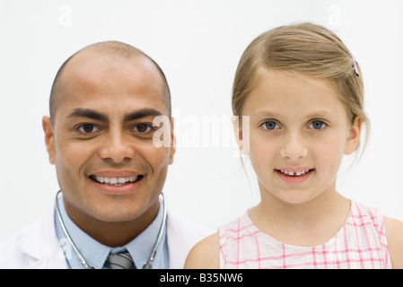 Männlichen Arzt neben Mädchen, beide lächelnd in die Kamera, Porträt Stockfoto