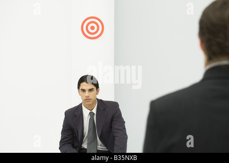 Professionelle Jüngling sitzt unten Bullauge, Chef im Vordergrund stehen Stockfoto