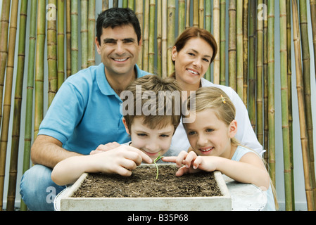 Familie zusammen, Topfpflanzen lächelnd in die Kamera Eltern, Kinder berühren Sämling Stockfoto