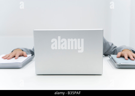 Mann versteckt Laptop setzen Palmen auf Stapel von Papier auf beiden Seiten Stockfoto
