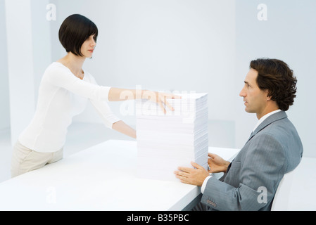 Berufstätige Frau und Unternehmer, die Austausch von hohen Papierstapel auf Schreibtisch Stockfoto