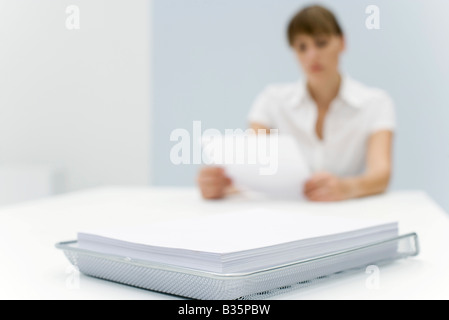 Stapel von Papier in Metalltablett, Frau lesen Dokument im Hintergrund Stockfoto