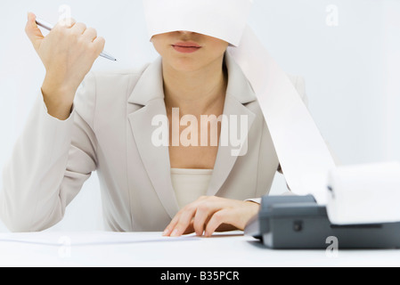 Frau sitzt am Schreibtisch mit dem Hinzufügen von Maschine Band um den Kopf gewickelt Stift klicken Stockfoto