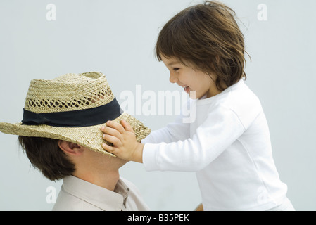 Kleiner Junge Hut über seines Vaters Augen herunterziehen Stockfoto