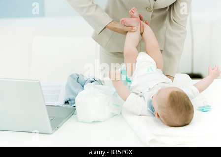 Berufstätige Frau wechselnden Babywindel auf Schreibtisch, beschnitten Ansicht Stockfoto