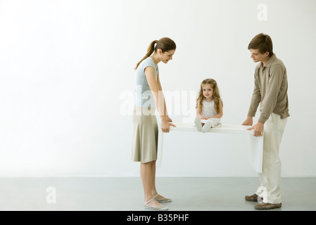 Junges Paar mit Tisch mit Tochter drauf sitzen Stockfoto