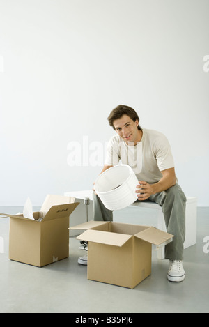Mann-Boxen, Auspacken, hält Lampenschirm, lächelnd in die Kamera Stockfoto