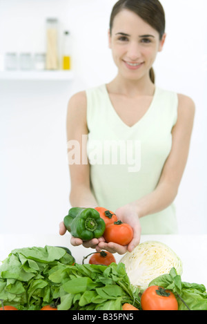 Frau, reife Tomaten und Paprika, verschiedene Gemüse im Vordergrund, lächelnd in die Kamera Stockfoto