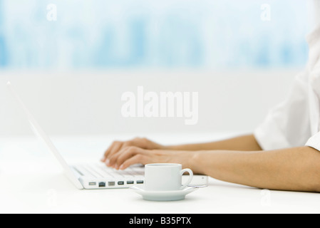 Frau mit Laptop-Computer, die Kaffeetasse in der Nähe, beschnitten Ansicht Stockfoto