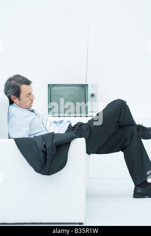 Geschäftsmann, ein Nickerchen im Sessel, mit gekreuzten Beinen slouching, Seitenansicht Stockfoto