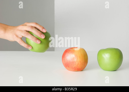 Hand, hob einen Apfel, zwei Äpfel, die sitzen in einer Reihe, beschnitten, Ansicht Stockfoto