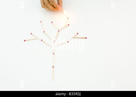 Hand mit einem beleuchteten Match, zünden Spiele in einem Baum Muster angeordnet Stockfoto