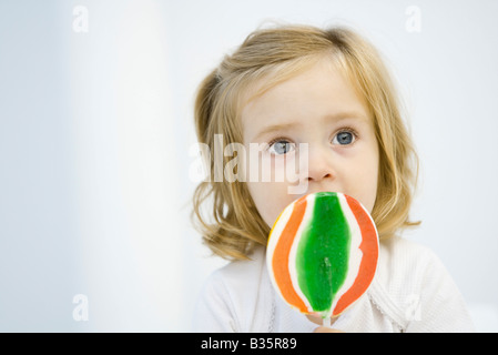 Kleine Mädchen essen große Lutscher, nachschlagen Stockfoto