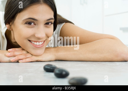 Junge Frau liegend auf Bauch, Kopf ruht, auf Arme hinter kleinen schwarzen Steinen in einer Linie Stockfoto