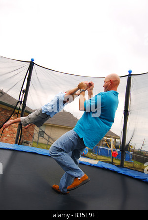 Seitenansicht eines Mitte erwachsenen Mannes spielt mit seinem Sohn auf einem Trampolin Stockfoto