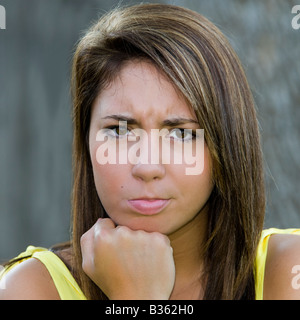 Ein hübsche, braune Haare, braune Augen, 16 Jahre alt Mädchen in einem gelben Kleid mit einem Schmollmund Ausdruck auf ihrem Gesicht. Stockfoto