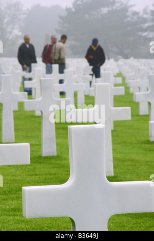 Gräber in den Militärfriedhof in Omaha Beach, Normandie, Frankreich. Eine Gruppe von Besuchern wird im Hintergrund gesehen. Stockfoto