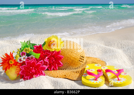 Flip Flops, Hut und Blumen am Strand Stockfoto