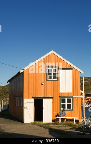 Abend in Sør-Gjæslingan in Vikna, Norwegen. Mann sitzt auf der Bank, die Reinigung von kleinen Platten aus Glas. Stockfoto