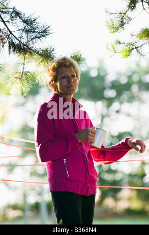 Reife Frau mit Becher im Schatten des Baumes Stockfoto
