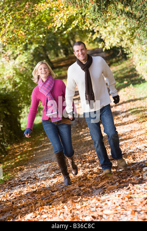 Paar im freien laufen weg im Park, die Hand in Hand lächelnd (Tiefenschärfe) Stockfoto