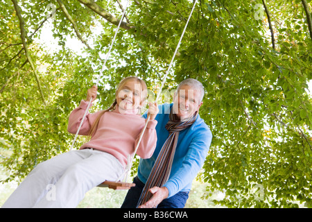 Großvater im Freien treibt Enkelin auf Schaukel und lächelnd (Tiefenschärfe) Stockfoto