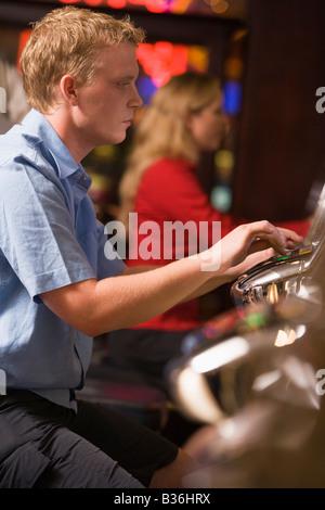 Mann im Casino spielen Spielautomat mit Menschen im Hintergrund (Tiefenschärfe) Stockfoto