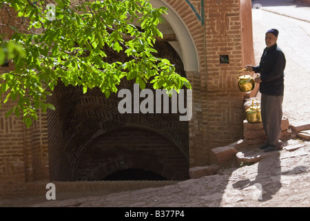 Lokale Mann füllen Wasserkocher aus der Zisterne im Abiyaneh Iran Stockfoto